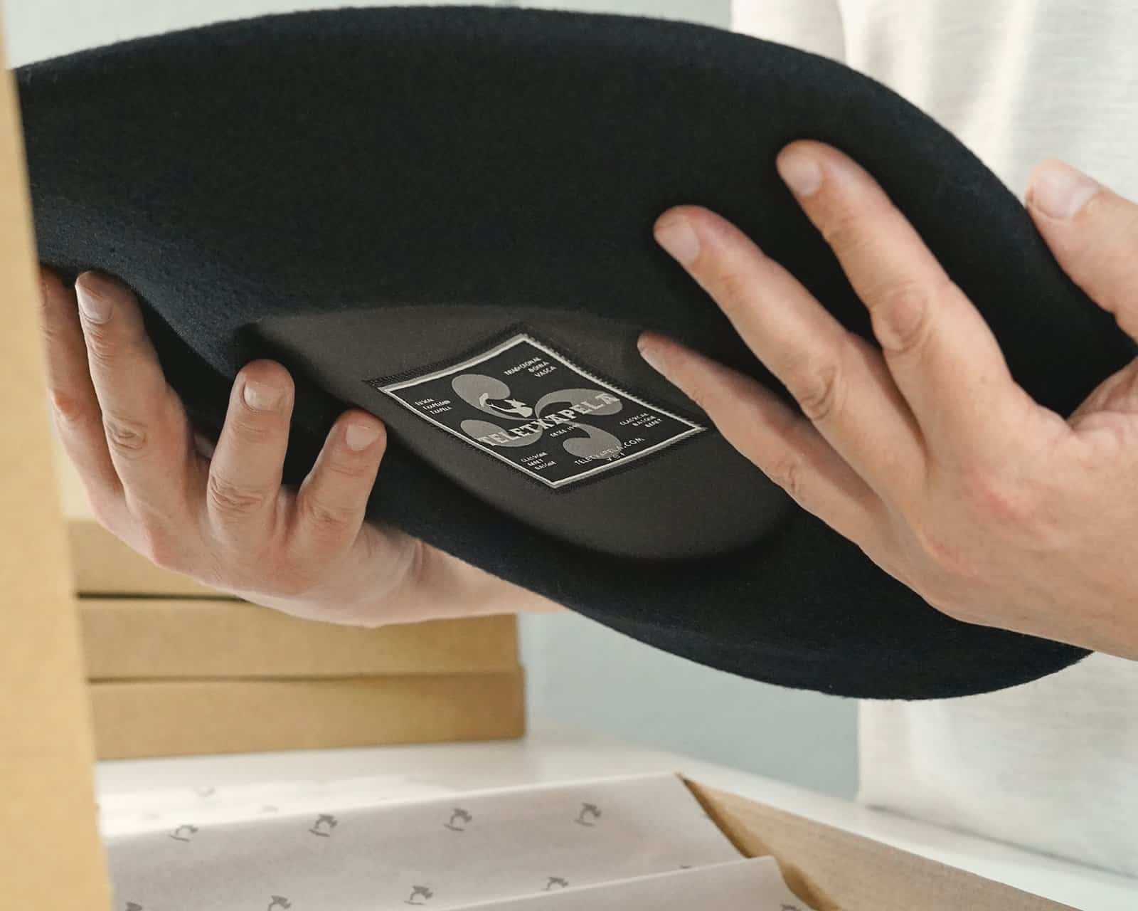 Txapela personalizada sostenida con las manos dejando ver el forro interior con la etiqueta cosida de Teletxapela