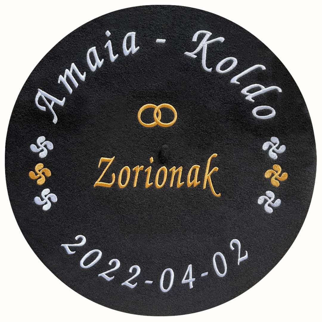 Txapela bordada para boda personalizada con nombres, fecha, frase, alianzas y lauburus en hilo color dorado y blanco