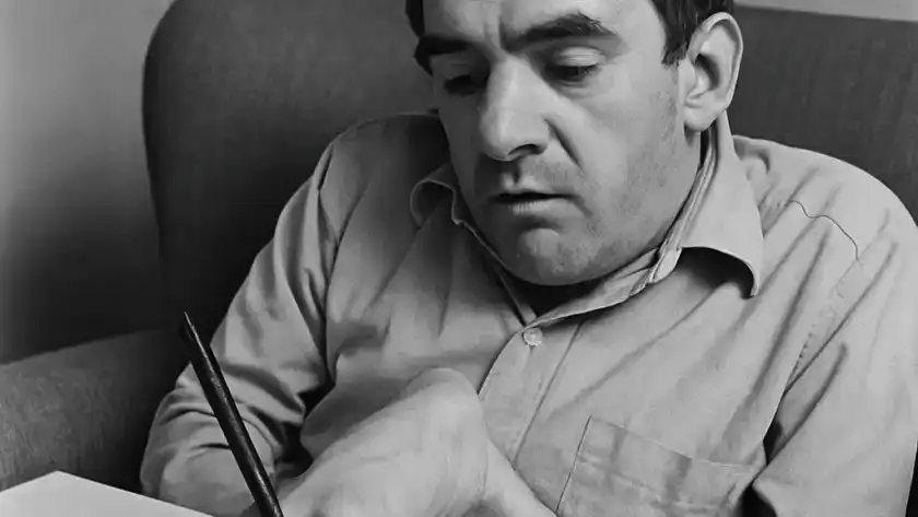 Black and white photo of Christy Brown writing with his foot.