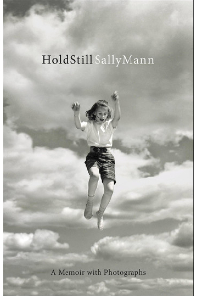 Black and white cover of 'Hold Still' memoir with a girl jumping in the sky.