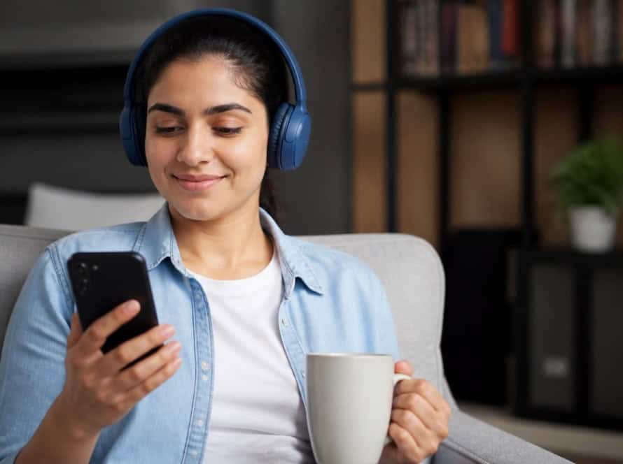 Young woman enjoying audiobooks with headphones and smartphone.