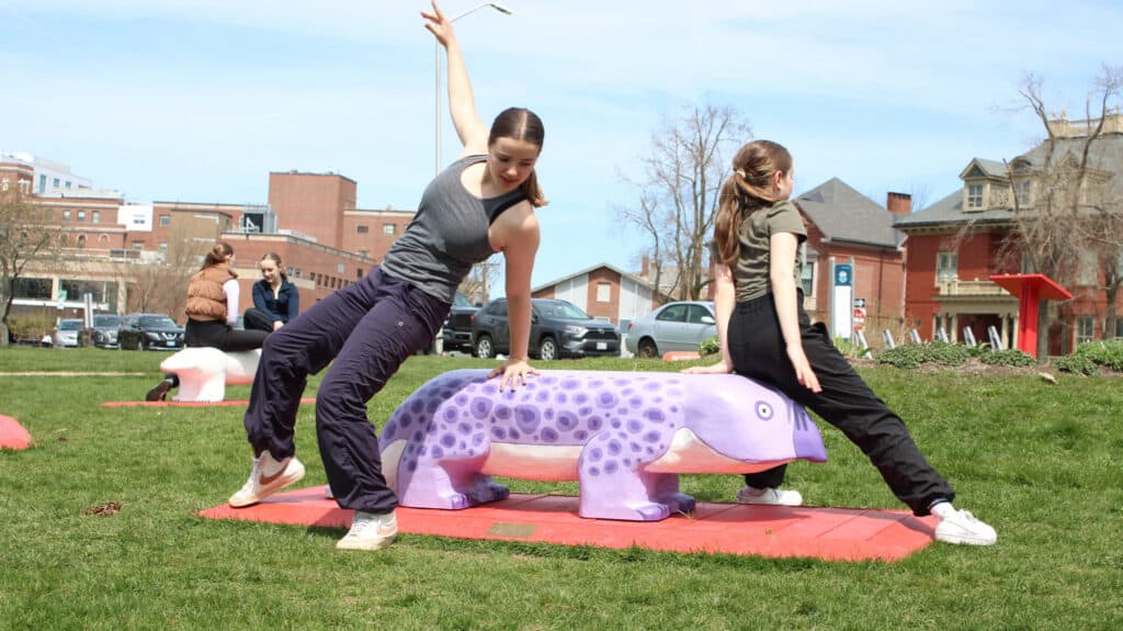 Youth dancers perform on a cosmic-themed sculpture in Portland park.