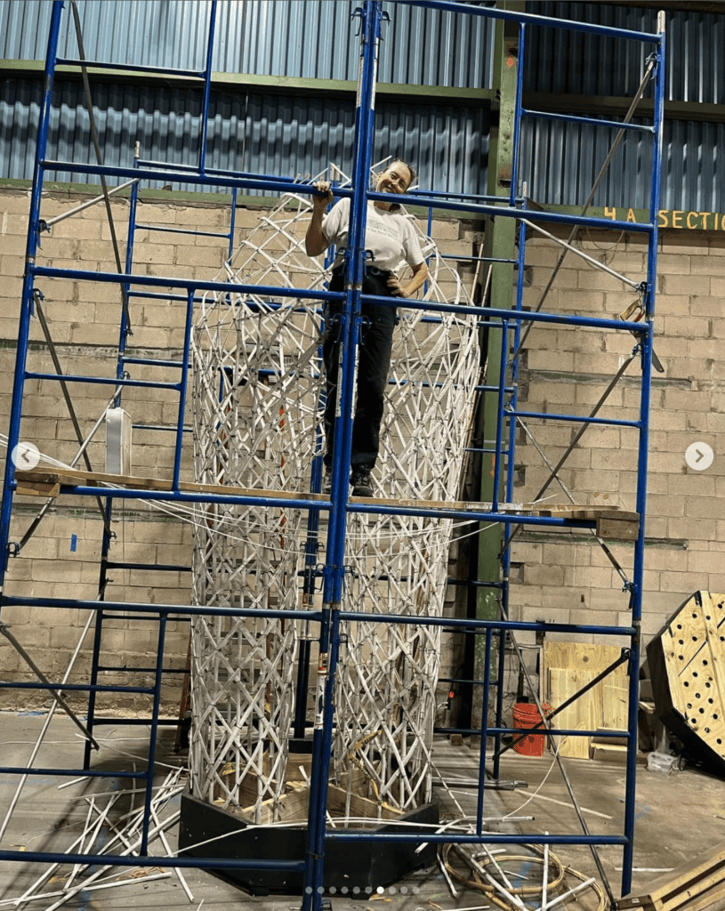 Artist working on the "Dancing for Joy" sculpture with scaffolding in a studio.