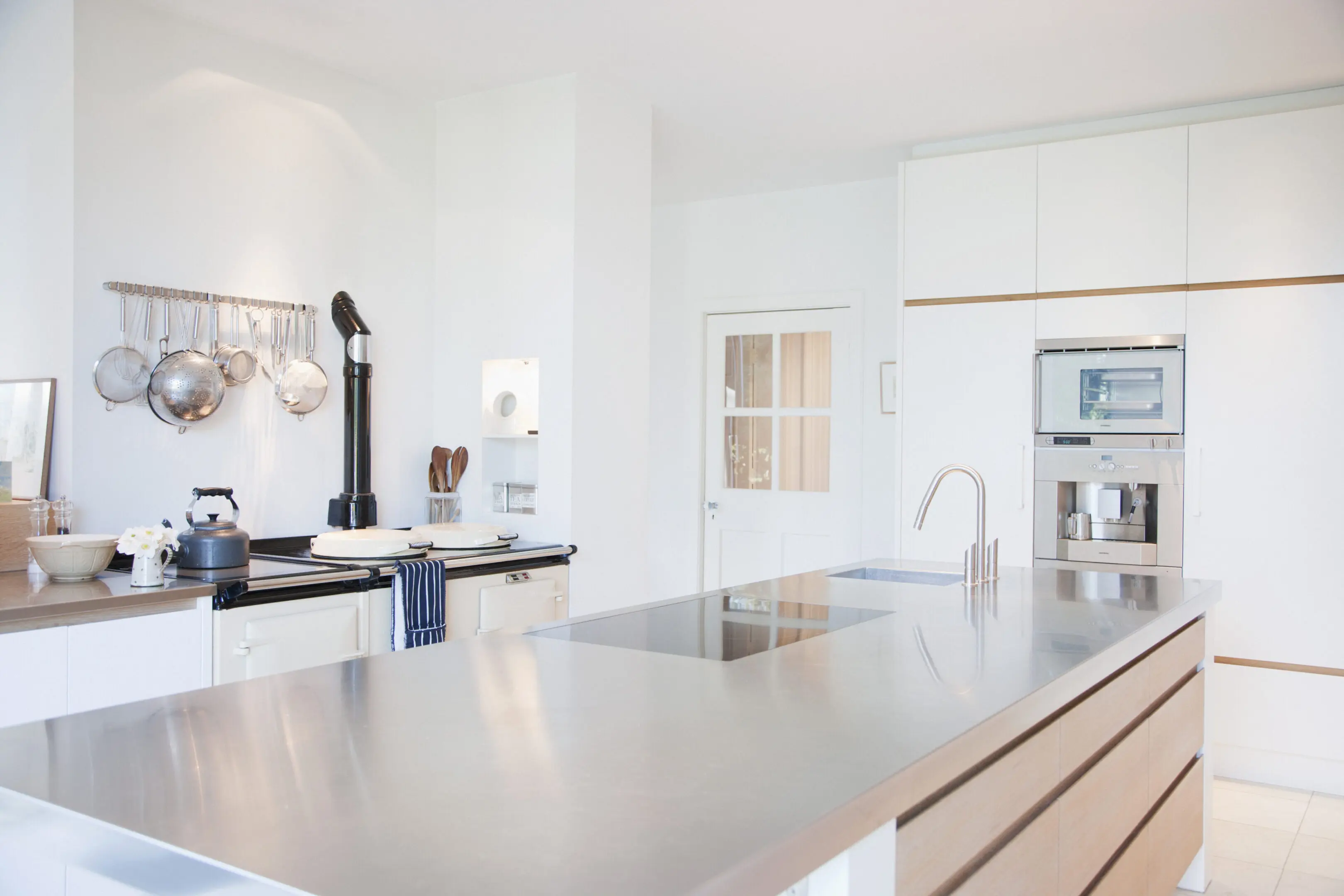 Bright, contemporary kitchen featuring sleek white cabinetry and a spacious stainless steel island.