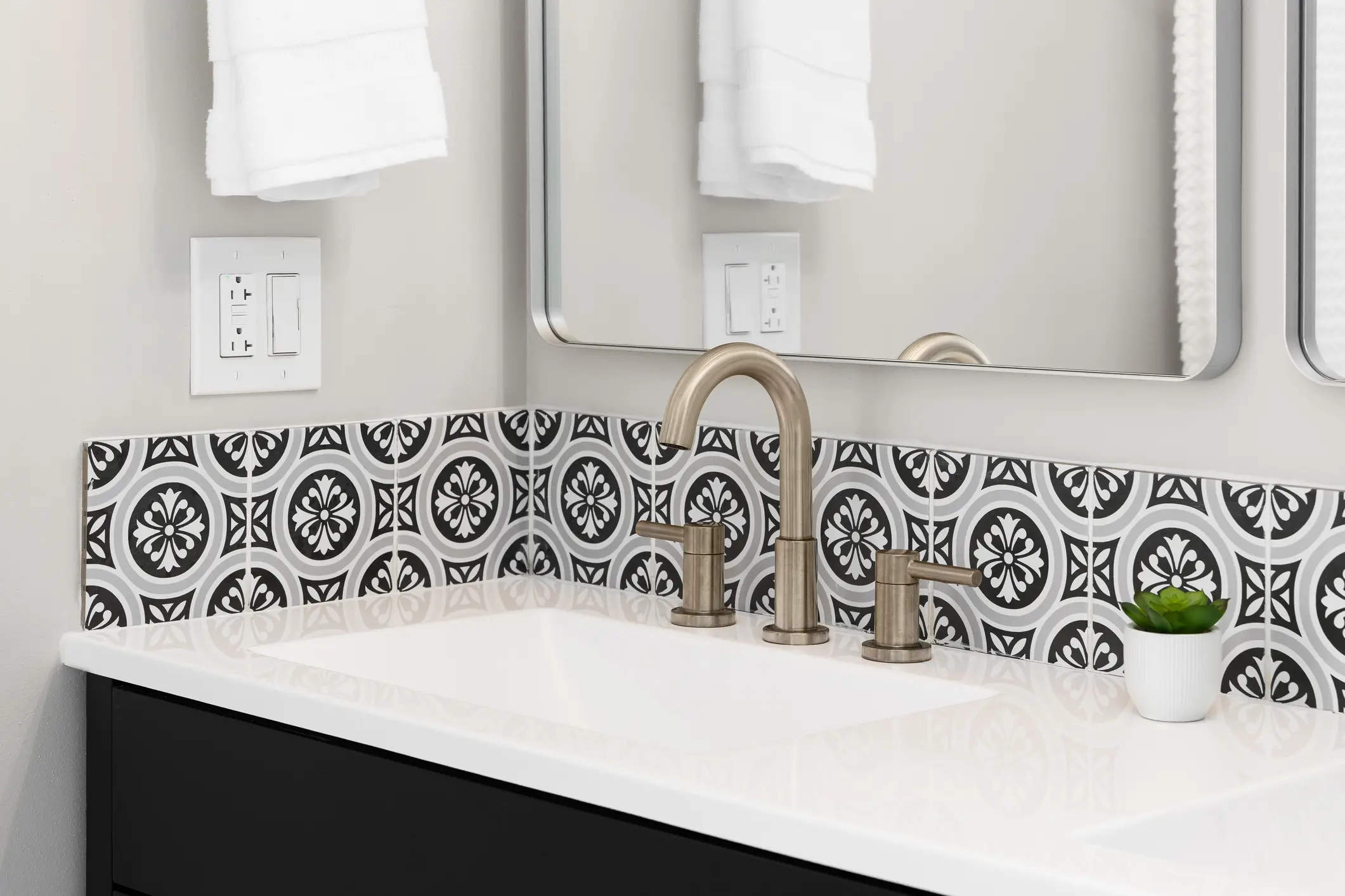Modern bathroom sink with stylish patterned tile backsplash and brushed nickel faucet.