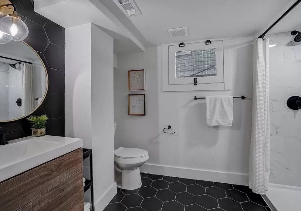 Modern bathroom with sleek fixtures, black hex tile floor, and white walls for a contemporary look.