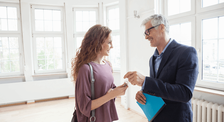 Real estate agent handing keys to smiling client in bright room, Walnut Creek, CA.