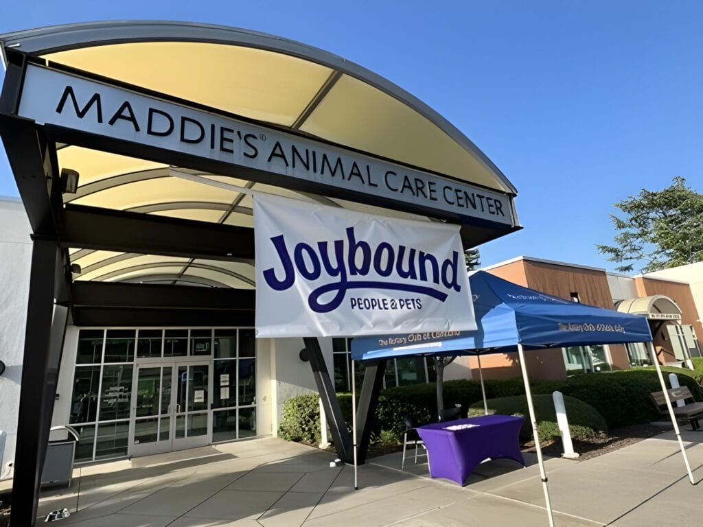 Bright outdoor view of Maddie's Animal Care Center with Joybound banner and event tent in Walnut Creek, CA.