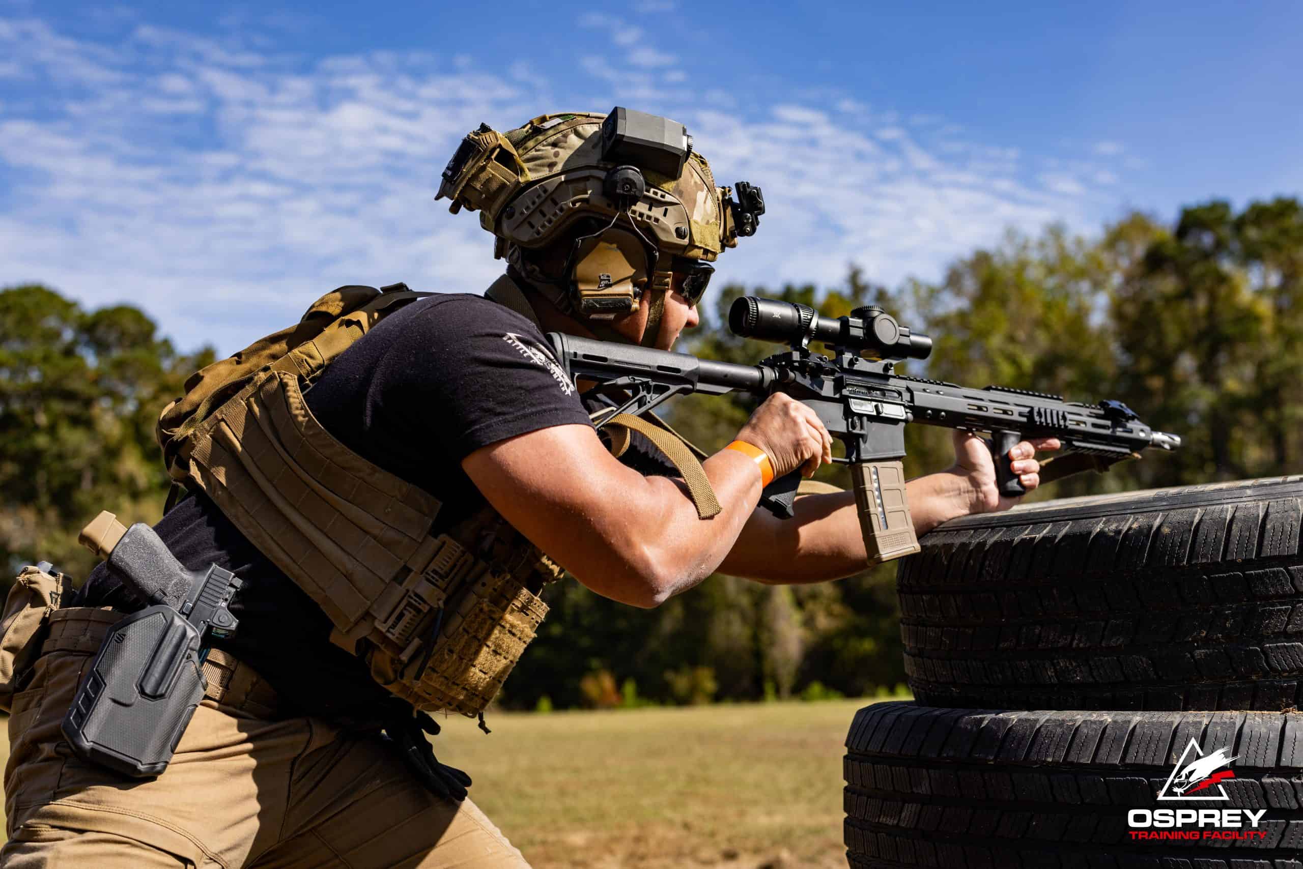 Competitor shooting an AR-15 off of stacked railroad ties at a 2 Gun competition hosted by Osprey Training Facility
