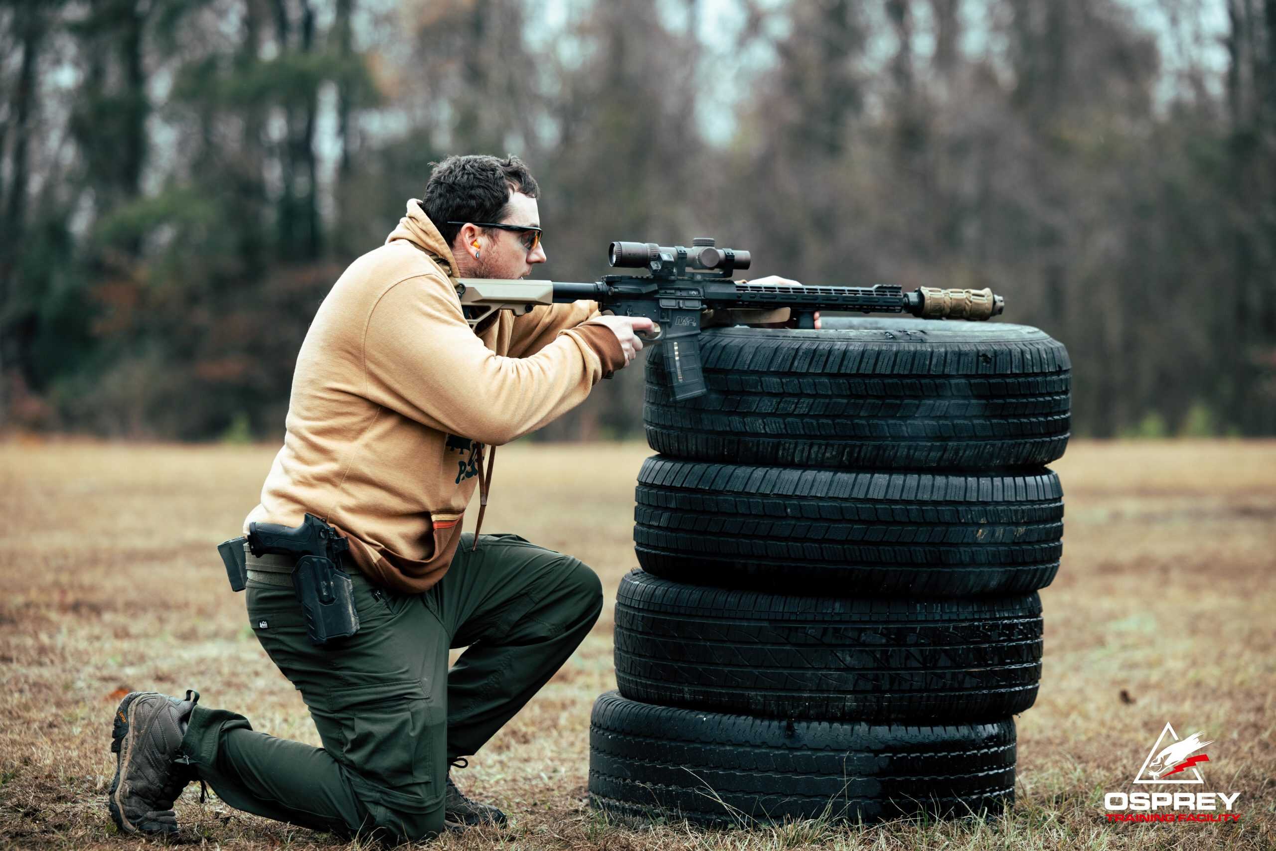 Competitor shooting an AR-15 off of stacked tires at a 2 Gun competition hosted by Osprey Training Facility