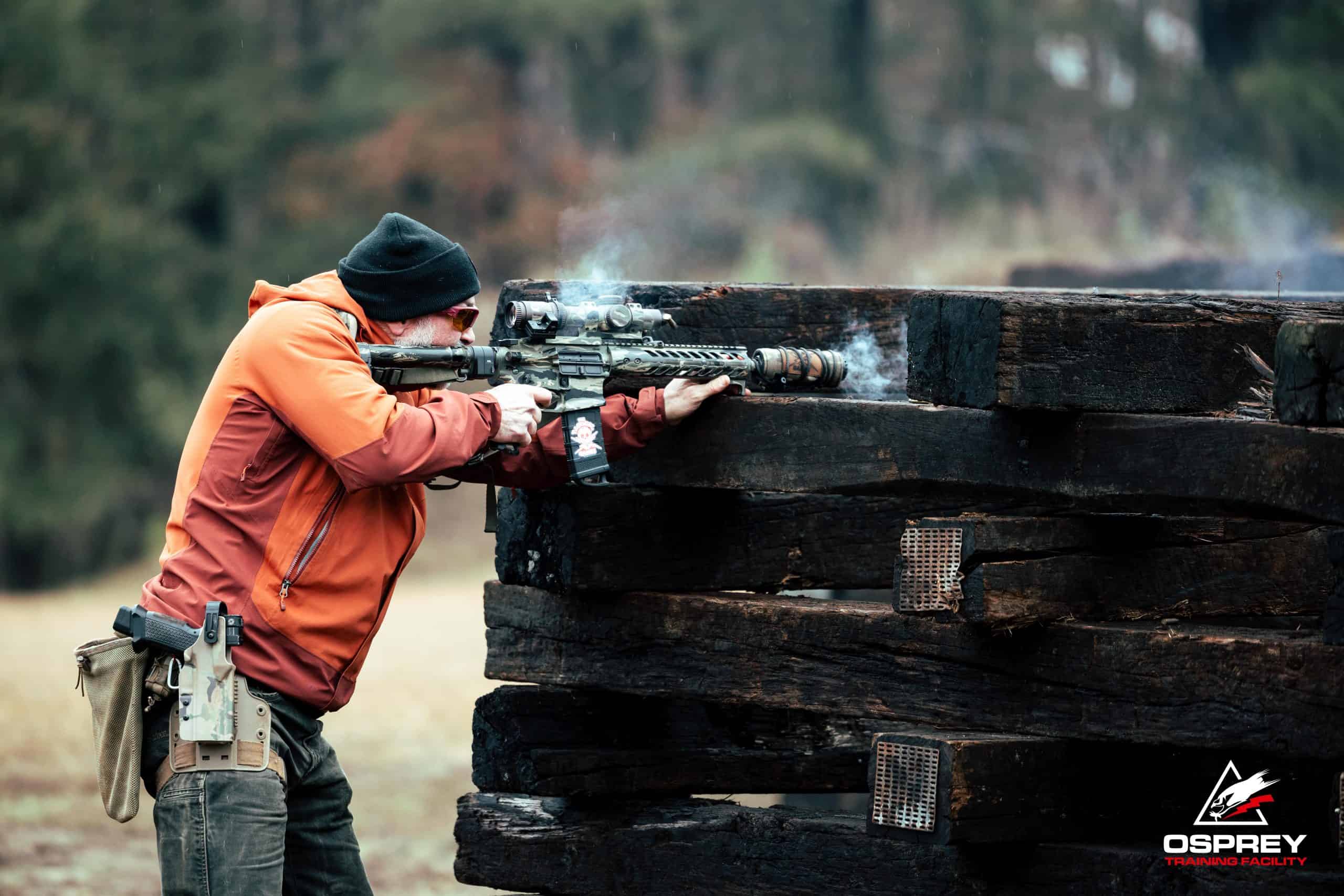 Competitor shooting an AR-15 off of stacked railroad ties at a 2 Gun competition hosted by Osprey Training Facility