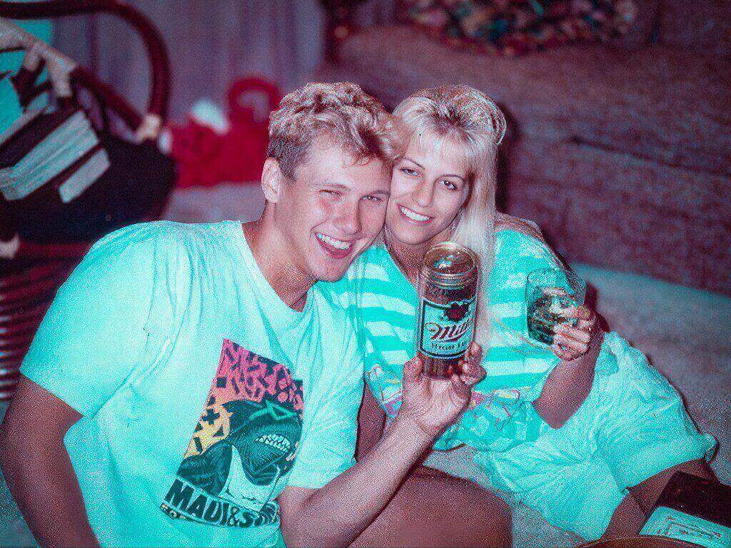The Ken And Barbie Killers: The Disturbing Case Of Karla Homolka And Paul Bernardo Smiling Couple In Casual Clothing Holding A Miller Beer Can, Enjoying A Relaxed Moment At Home.