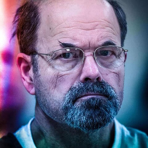 Close-up of a man with glasses showing the dark side of human nature and evil.