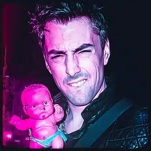 Eerie image of a man holding a disturbing doll with neon lighting.