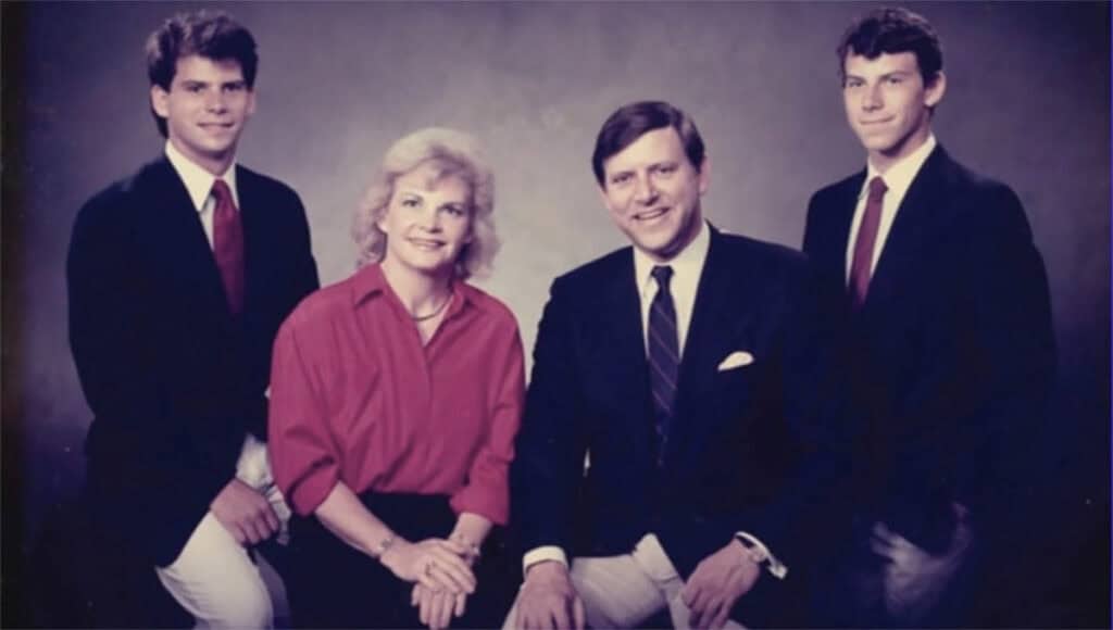 Portrait Of A Family With Two Sons In Suits, Parents Seated, Mother In Red Blouse, Father In Dark Suit, Formal Setting.