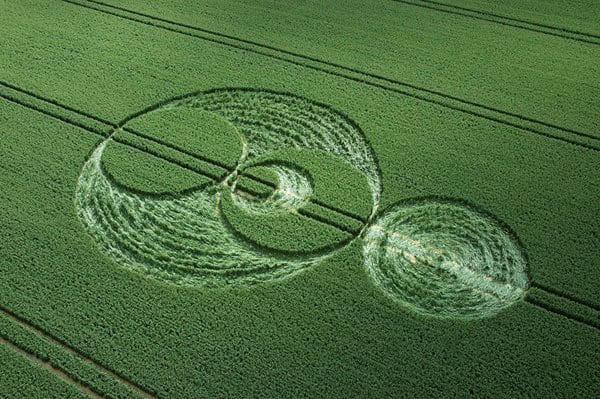 Aerial view of a wheat field with crop circles and geometric patterns.