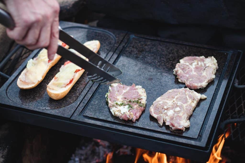 Grilling delicious meats and sandwiches on a flat-top grill at The Flames Galore Restaurant for flavorful barbecue.