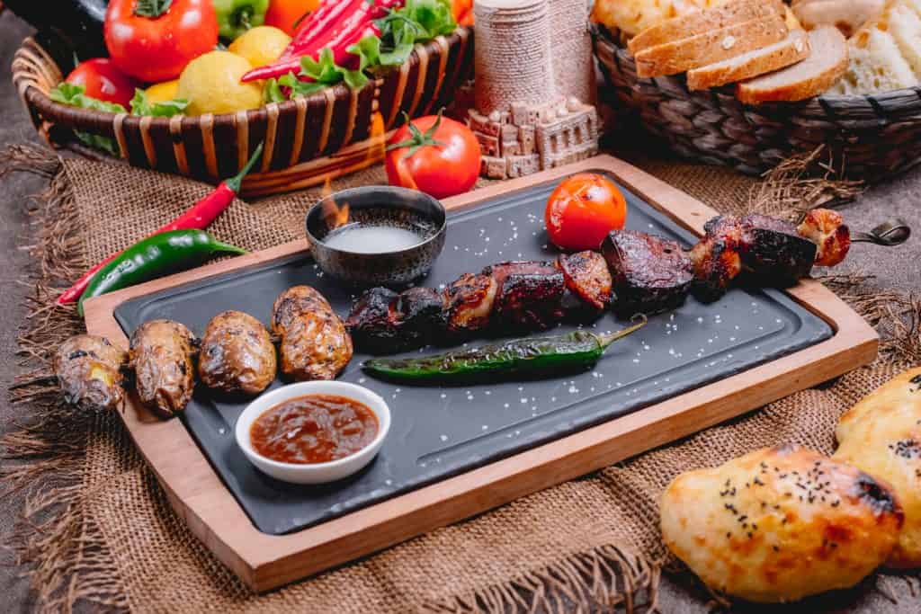 Juicy grilled kebabs with roasted vegetables and spicy sauces at The Flames Galore Restaurant.