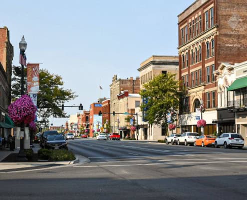 Colorful downtown Fostoria street with historic architecture and blooming floral displays, showcasing local community charm.