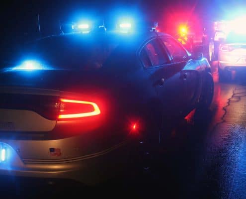 Emergency police car with flashing lights on a wet road during night time.