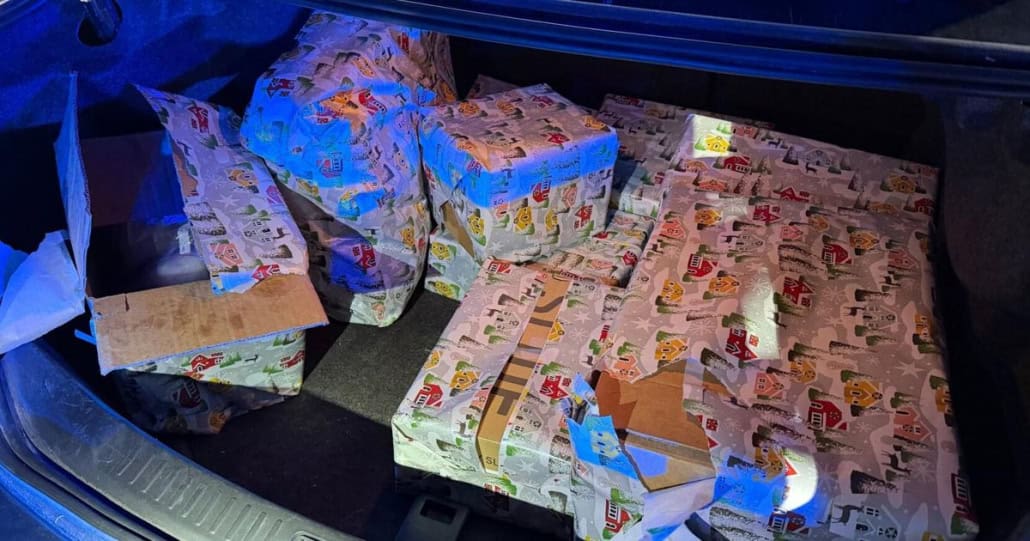 Colorful holiday wrapping paper with presents in vehicle trunk during Christmas season.