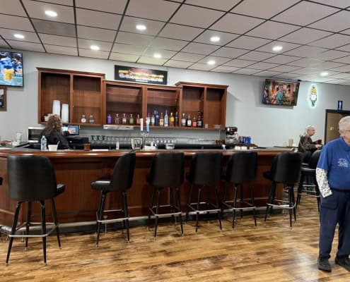 Bar area with TV screens, drinks, and seating at The Fostoria Free Press.