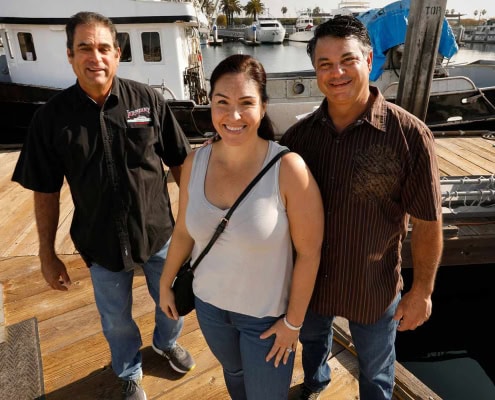 Photo of happy people at a marina with boats and yachts, showcasing local boating and waterfront lifestyle.