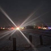 Dark night scene with emergency lights creating starburst effect, police and fire vehicles on scene in Fostoria.