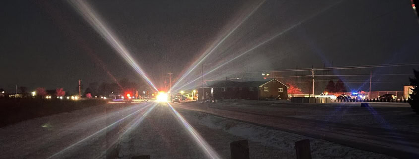 Dark night scene with emergency lights creating starburst effect, police and fire vehicles on scene in Fostoria.