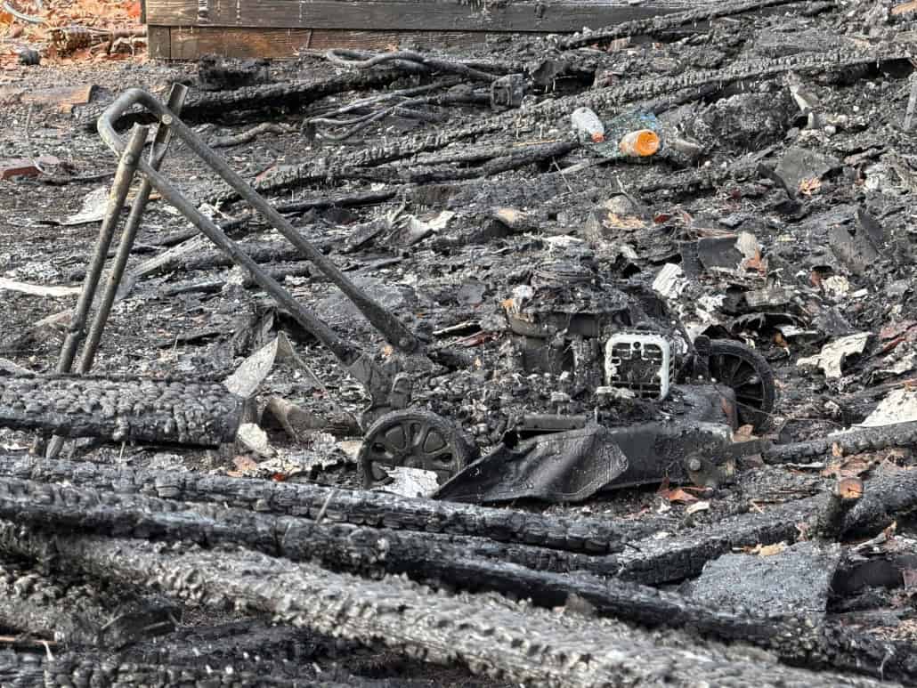Charred motorcycle remains in burnt debris after fire damage.