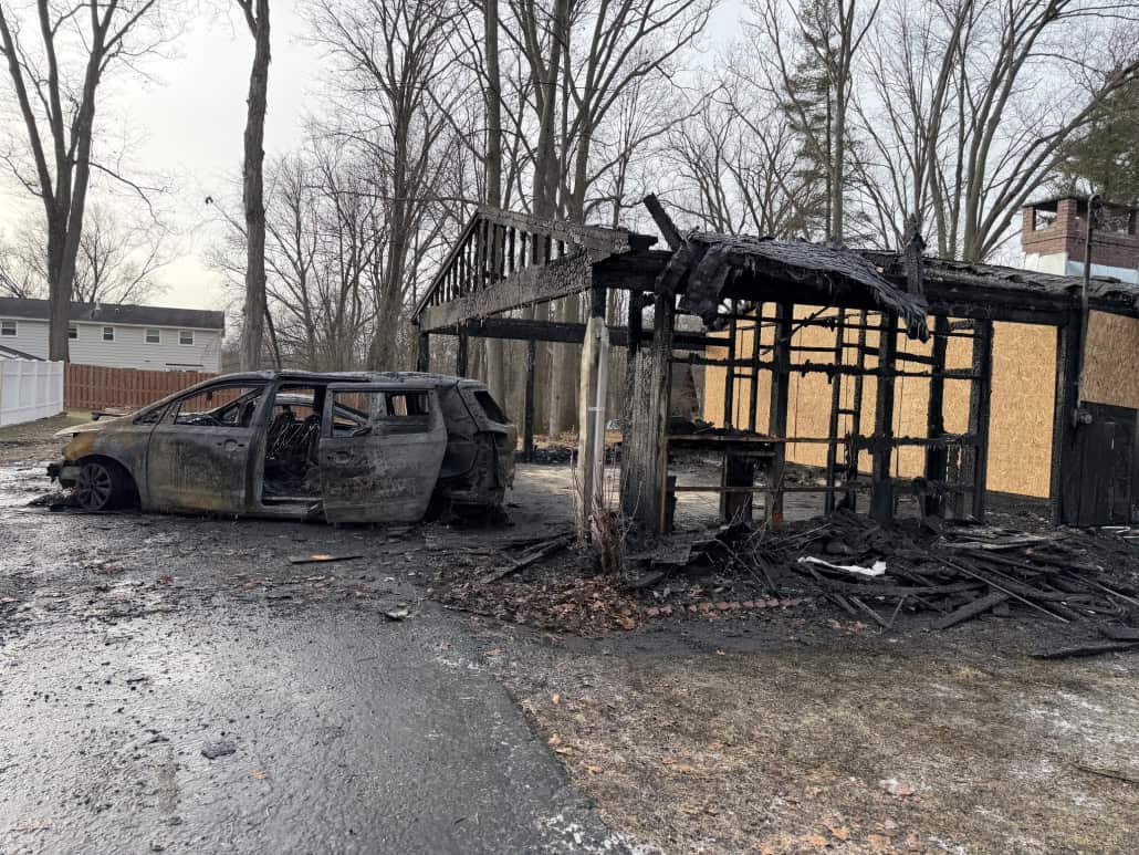 Charred car and burned-down structure after fire incident in Fostoria, Ohio.