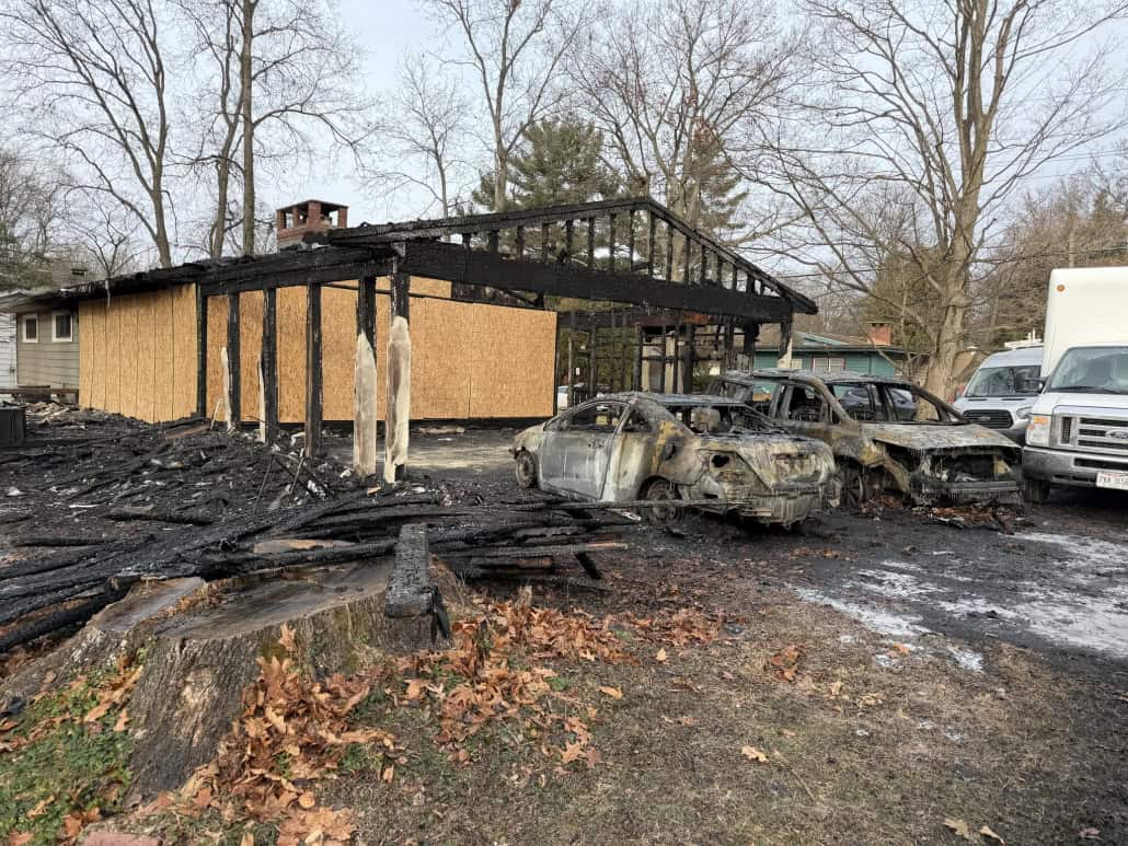 Charred and burnt house with damaged vehicles after fire incident in Fostoria.