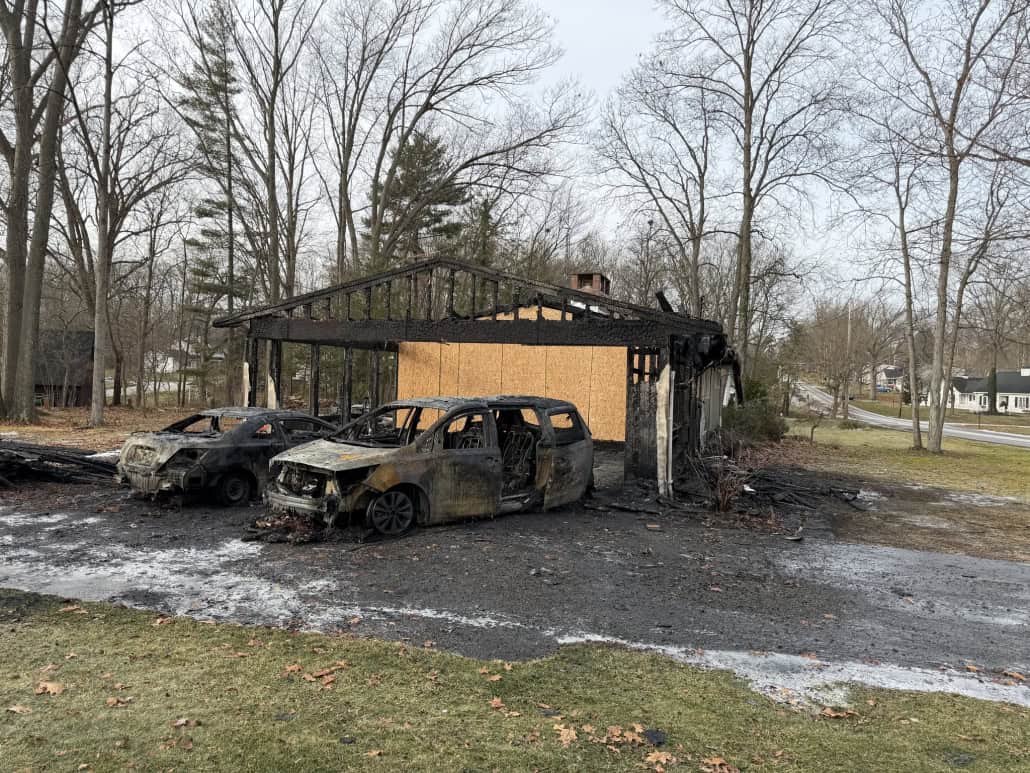 Charred house remains and melted vehicles after fire destruction in Fostoria, Ohio.