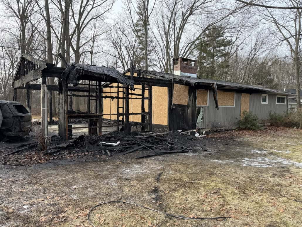 Burned house with charred exterior, remnants of fire aftermath, and damaged property.