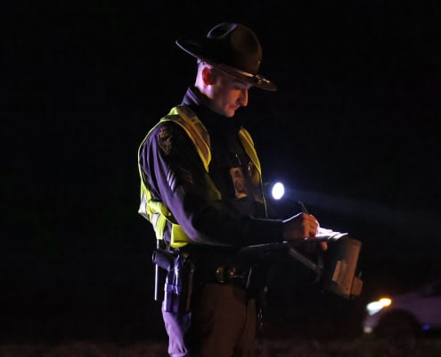 Police officer writing reports during night patrol.
