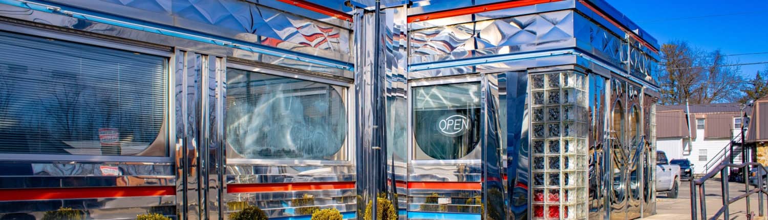 Retro diner with shiny chrome facade and neon "Open" sign.