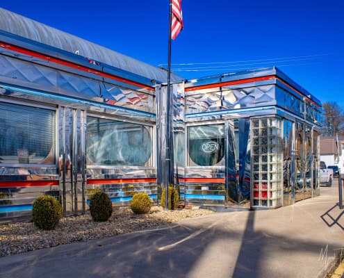 Retro diner with shiny chrome facade and neon "Open" sign.