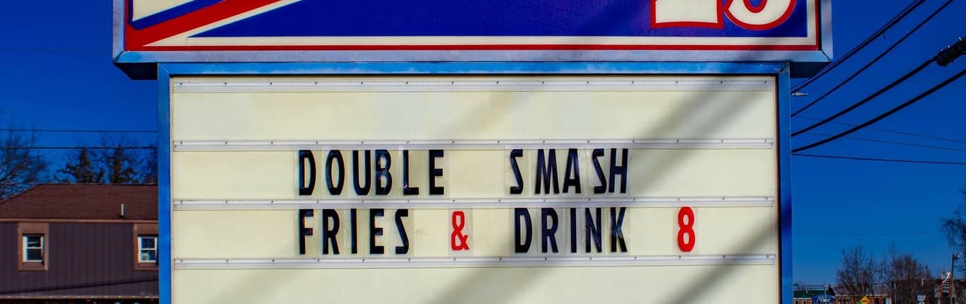 A vibrant diner sign in Fostoria, Ohio, featuring the restaurant name and special menu offers for locals.