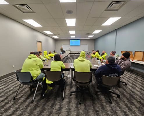 Conference room with people in high-visibility vests attending a meeting, highlighting community engagement.