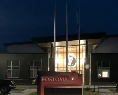 Fostoria Free Press building at night with illuminated sign and logo.