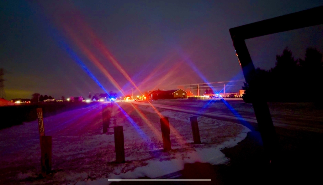 Colorful emergency lights at night in Fostoria, Ohio, with a snowy landscape and police vehicles.