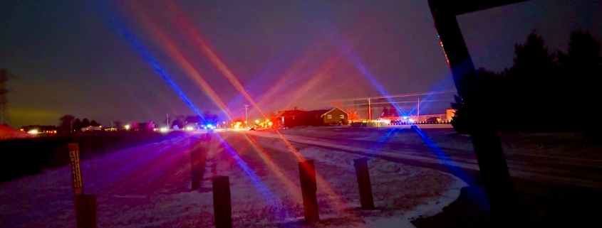 Colorful emergency lights at night in Fostoria, Ohio, with a snowy landscape and police vehicles.