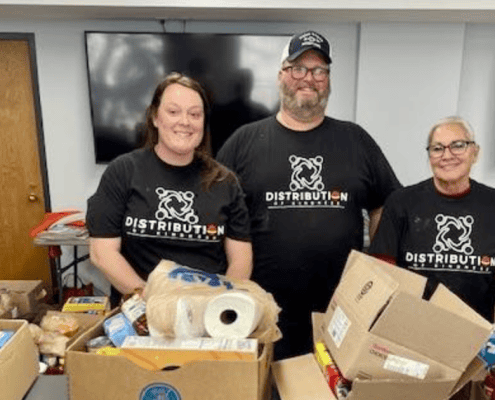 Volunteers in T-shirts with “Distribution” logo sorting food boxes for community pantry.