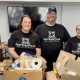 Volunteers in T-shirts with “Distribution” logo sorting food boxes for community pantry.