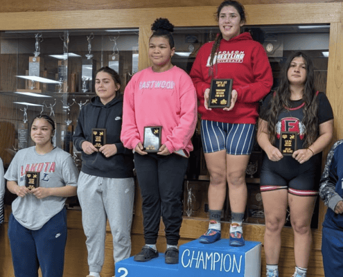 Young female athletes showcasing wrestling achievements at The Fostoria Free Press.