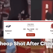 Crowd watches intense basketball game at Fostoria High School gymnasium.