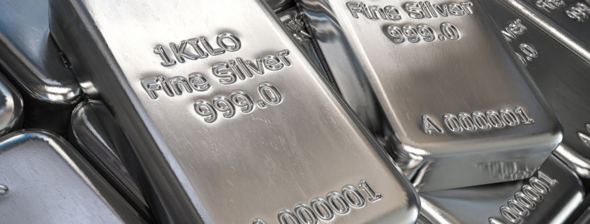 Shiny silver silver bars with inscriptions, stacked closely together.