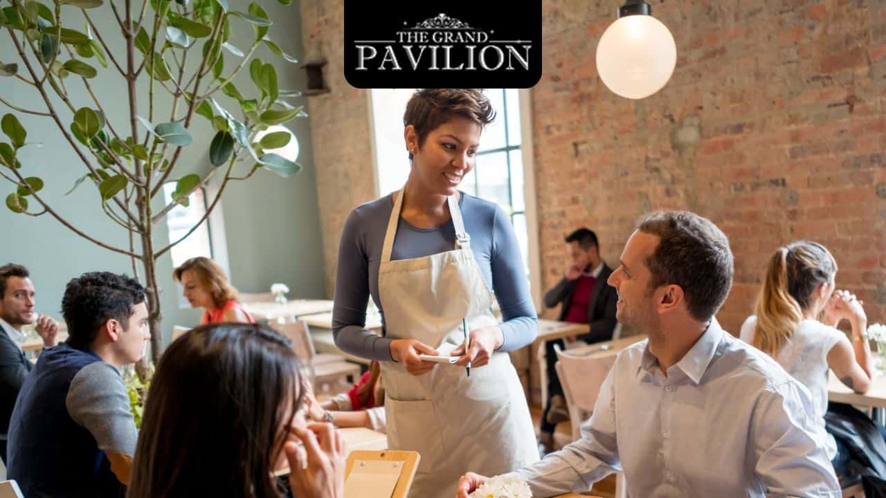 Beautiful woman waitress serving smiling couple at restaurant, cozy modern dining space with brick wall interior, The Grand Pavilion signature style, casual and elegant atmosphere.