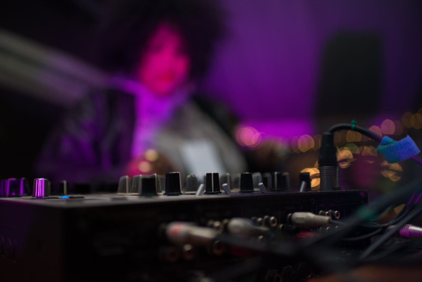 Image of a DJ mixing music at The Live Lounge, with colourful stage lighting creating an energetic atmosphere for live music and DJ performances in the UK.