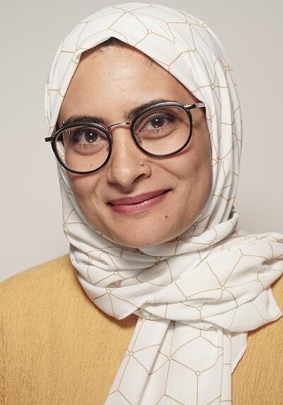 Nama Khalil Smiling person wearing white headscarf and glasses